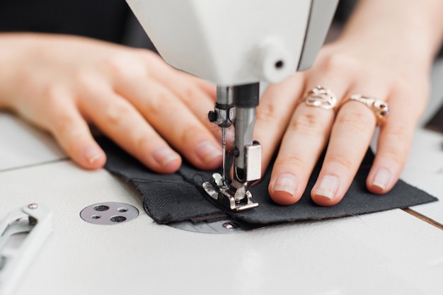 Woman hands with fabric at sewing machine.