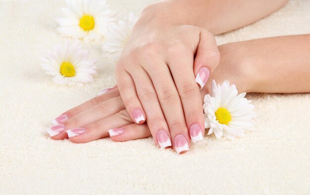 Woman hands with french manicure and flowers on towel