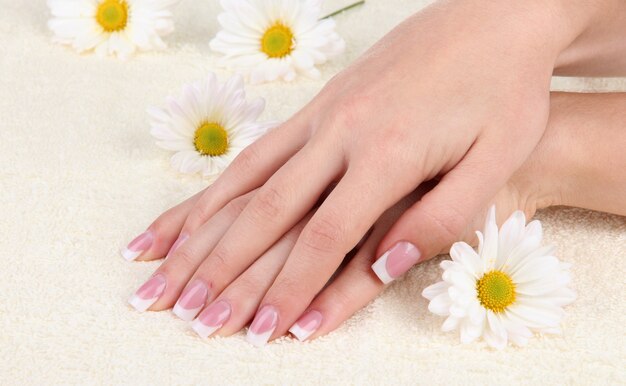 Woman hands with french manicure and flowers on towel