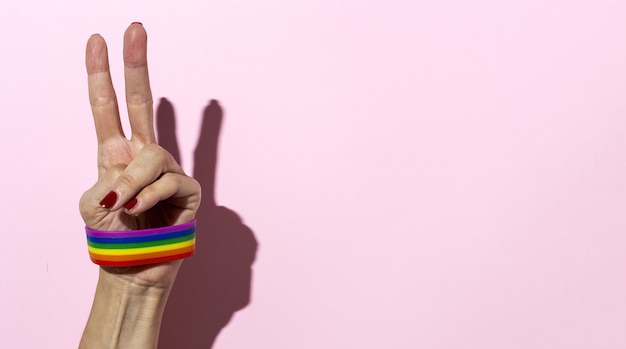 Foto mani di donna con braccialetto lgbt su sfondo rosa