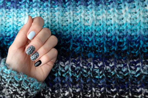 woman hands with manicure in knitted wool sweater