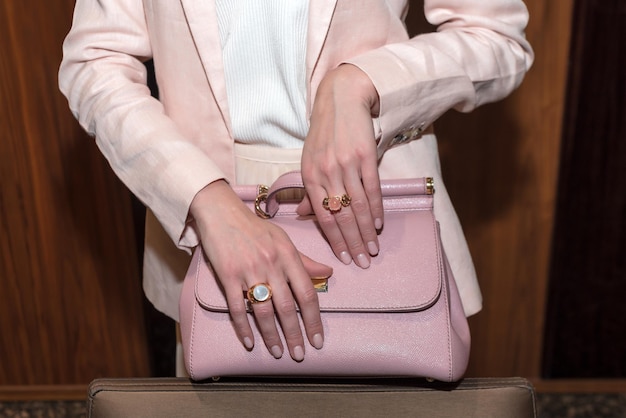 Photo woman hands with manicure and luxury jewelry rings close up of trendy leather pink bag with female h...