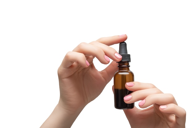 Woman hands with pink manicure. Female holding essential oil bottle. Female healthcare wellness concept.