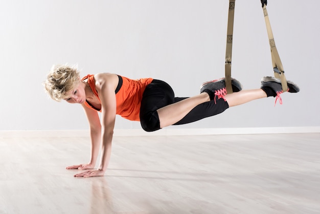 Woman on hands with training trx rings around ankles