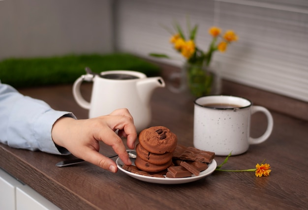 사진 흰색 주전자 차 컵과 choccolate 쿠키 여자 손