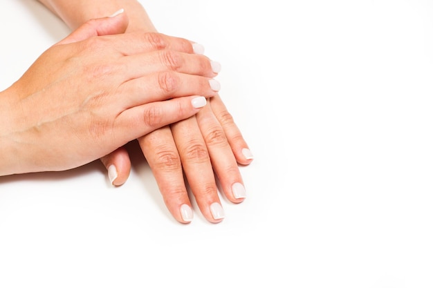 Woman hands with white nails on a white background with copy space