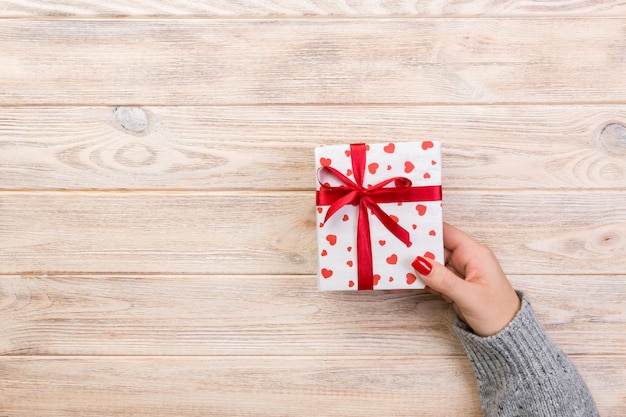 Woman hands with wrapped present with red ribbon