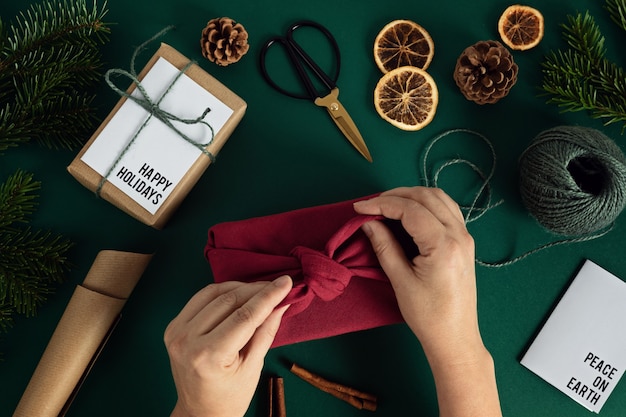 Foto mani della donna che avvolgono il regalo di furoshiki