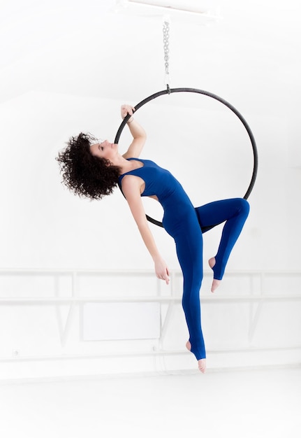 Woman hanging in aerial ring isolated on white