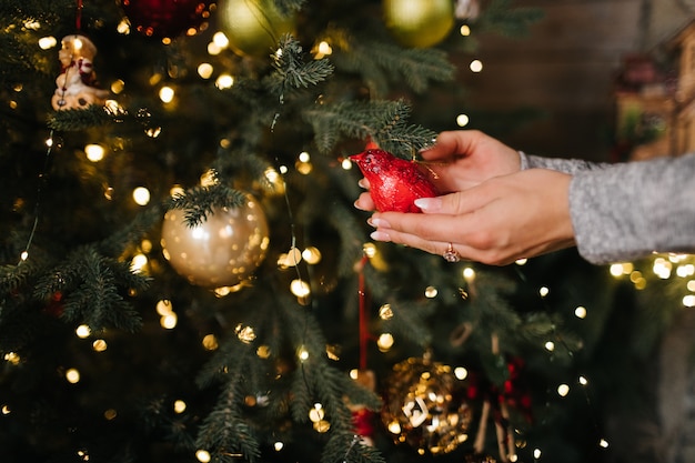 사진 bokeh 빛을 가진 나무에 크리스마스 공을 거는 여자