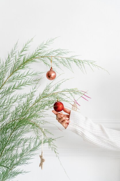 Photo woman hanging a red bauble on a christmas tree