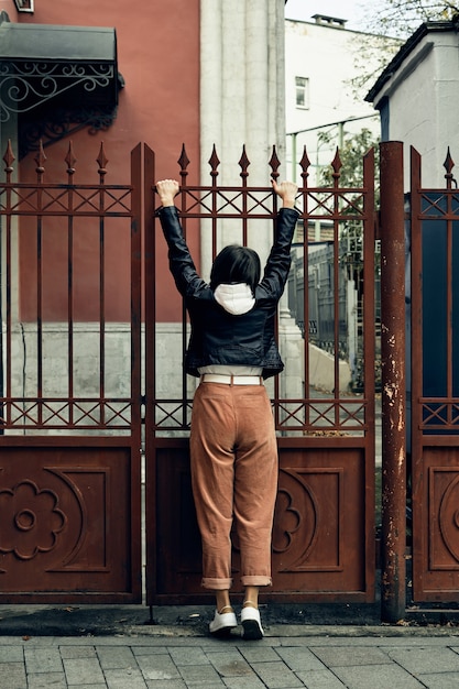 woman hangs in her arms on a metal fence.