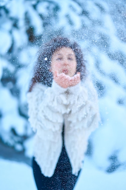 A woman happily playing with snow in a snowcovered winter forest