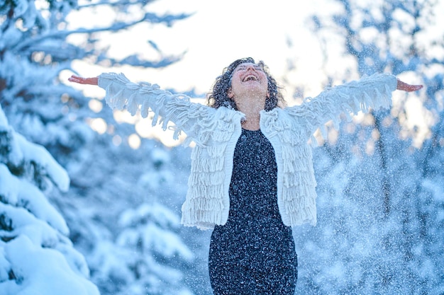 A woman happily playing with snow in a snowcovered winter forest