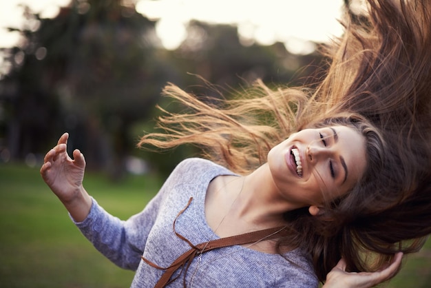 Photo woman happy and dancing with hair in wind female person in nature with carefree creative and moving motion summer enjoy or student on holiday with excited head and smile for vacation freedom