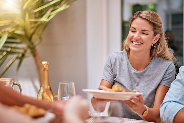 Photo woman happy holding dinner plate dinner table celebration and people group with bottle champagne on holiday festive girl supper smile happiness and food family home party or luxury restaurant