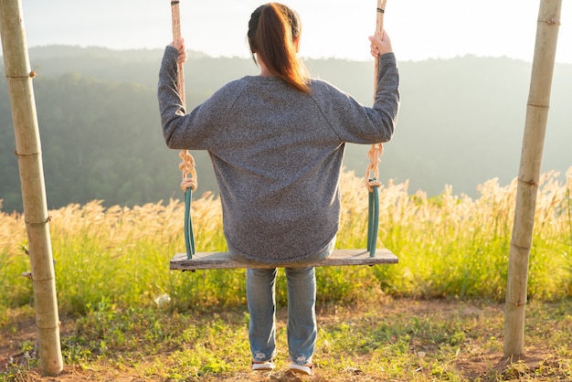 Woman happy on swing in sun light.