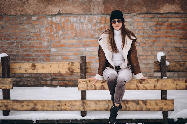 Woman happy in winter sitting on fence