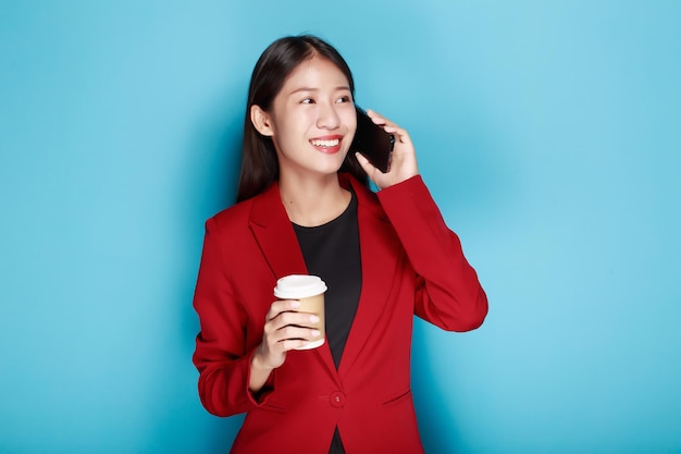 一人の肖像画の背景として青い背景を持つ女性が笑顔で携帯電話を手に持っています