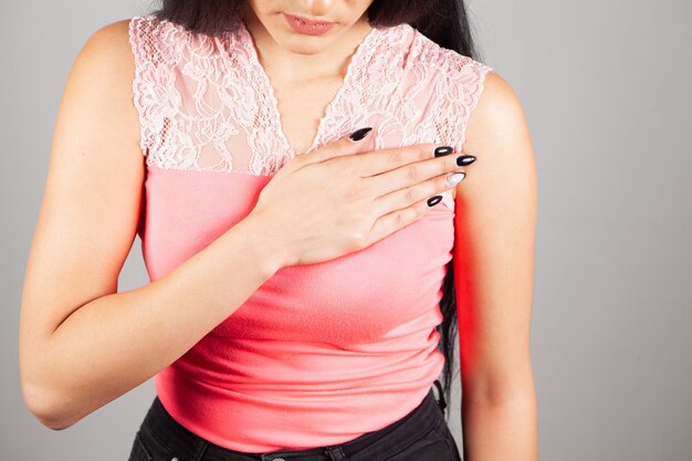 Woman has chest pain on gray background