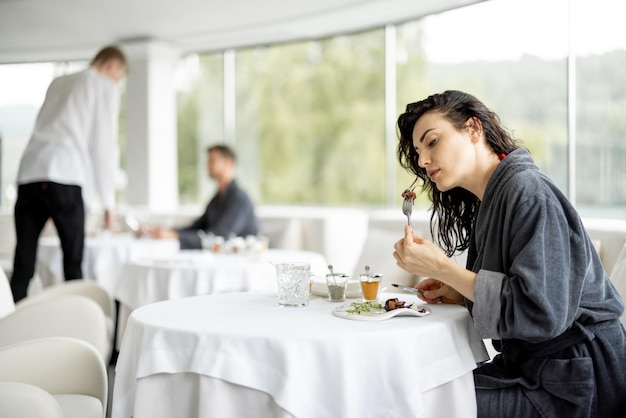 女性は料理のレストランで夕食を食べます