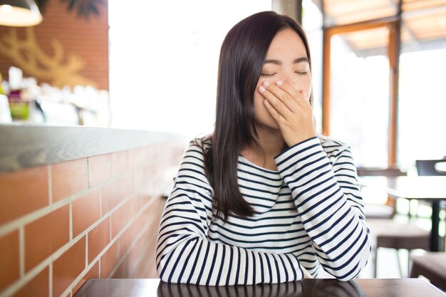 カフェでくしゃみをする女性