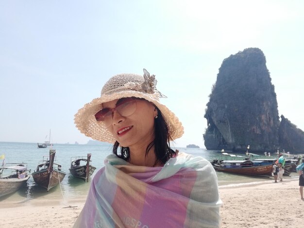 Foto donna con un cappello in spiaggia durante l'estate