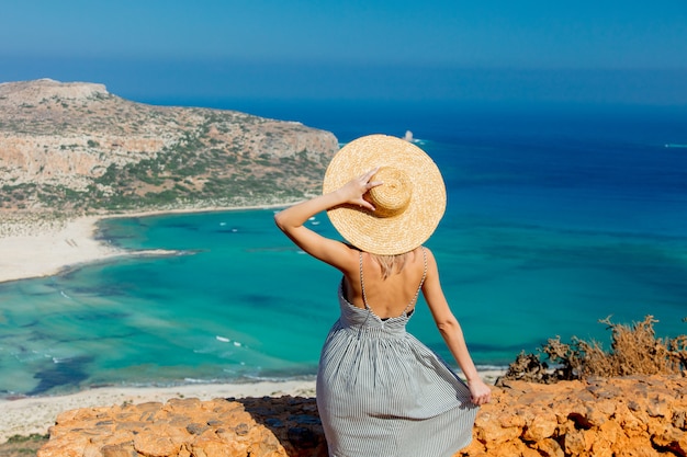 Woman in hat and dress at the coastline