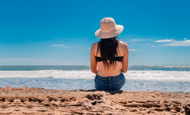 woman in hat from back to the sea girl in hat looking to the sea a girl watching the sea