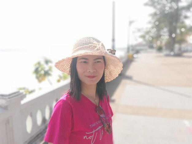 Woman in hat looking away against sea