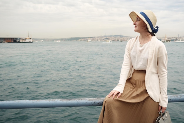 Foto donna con cappello e gonna midi in riva al mare, tonica