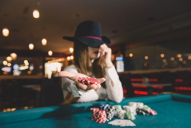 Woman in hat offering casino chips on palm