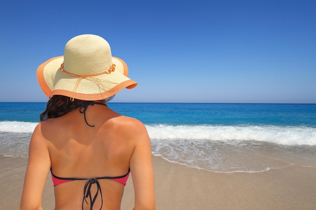 Woman in hat overlooking the seascape from the beach