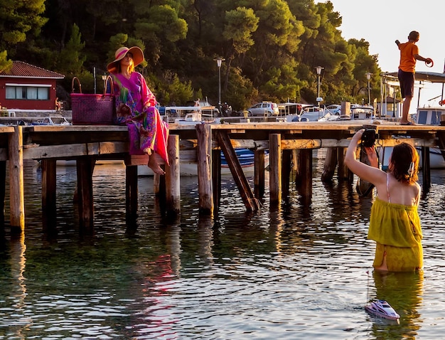 Foto una donna con un cappello posa per una foto sull'isola di skiathos in grecia al tramonto