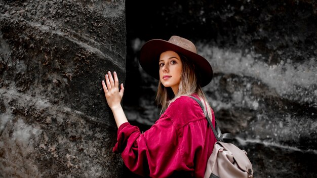 Woman in hat and red shirt near stones in a mountains