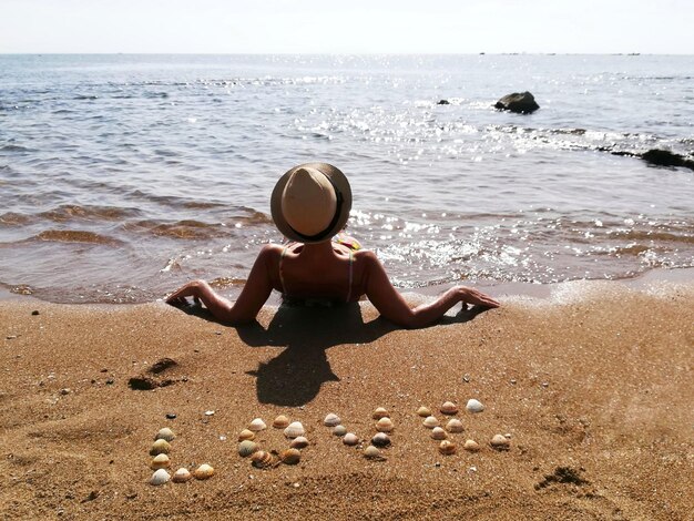 Photo woman in hat relaxing against text at beach