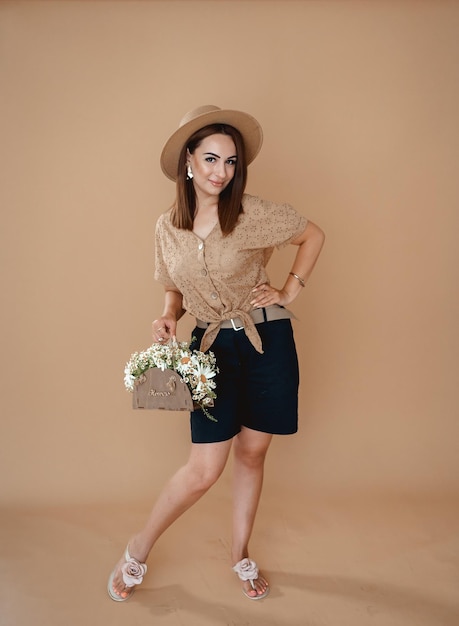 a woman in a hat a shirt with daisies on a beige background