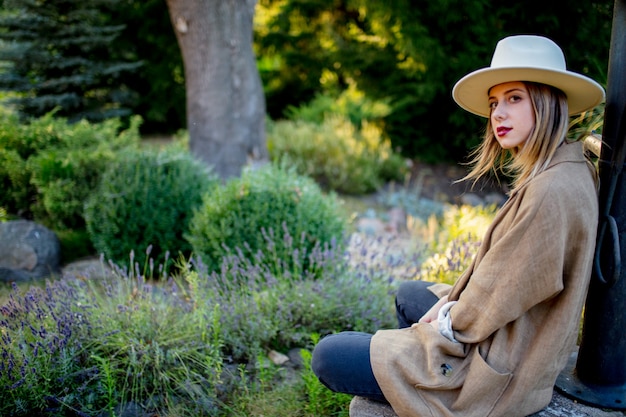 Woman in hat sitting near Lavender flowers