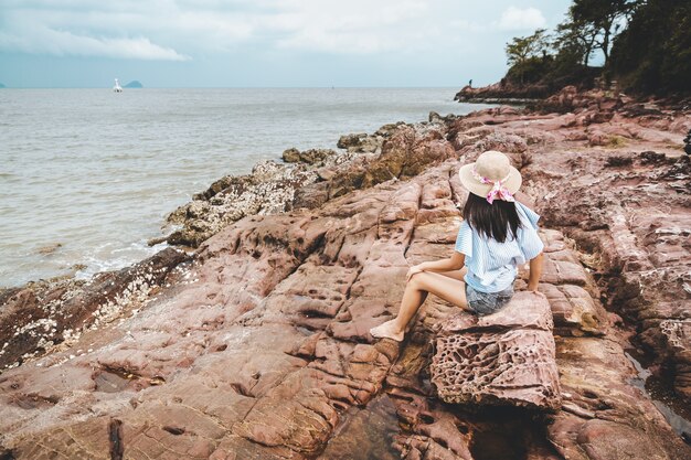 Woman in hat sitting on a rock