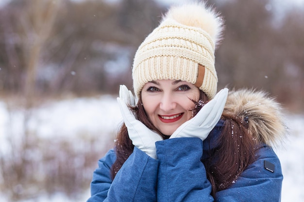 Woman in a hat smiling on the background of a winter landscape