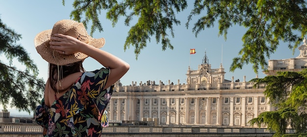 Woman in hat stands and looking at Royal Palace Madrid Spain Young woman enjoy summer vacation