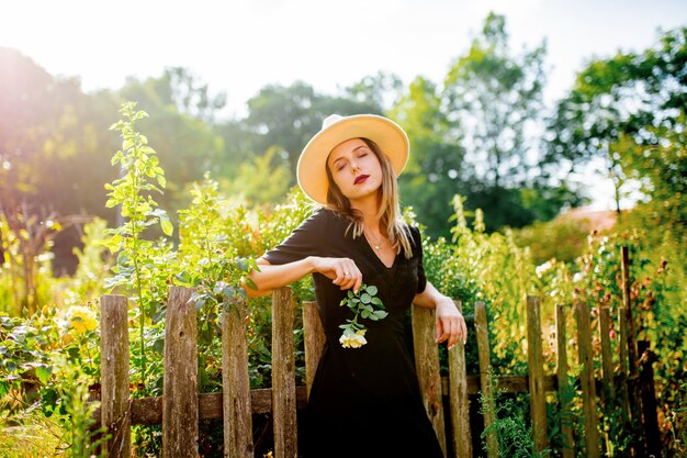 Woman in hat in a summertime countryside garden 