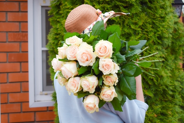 Woman in hat with a bouquet of flowers.