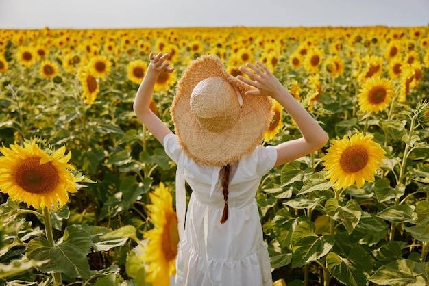 Woman in hat with raised hands field of sunflowers nature summer