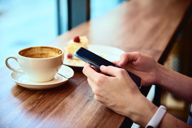 女性はカフェで朝食をとるカフェでスマートフォンを使用