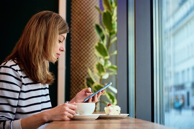 La donna fa colazione al bar usa lo smartphone al bar