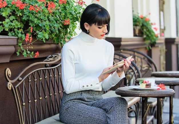 Woman have drink enjoy good book cafe terrace Literature for female Girl drink coffee read book Mug of good coffee and pleasant book best combination for perfect weekend Self improvement concept