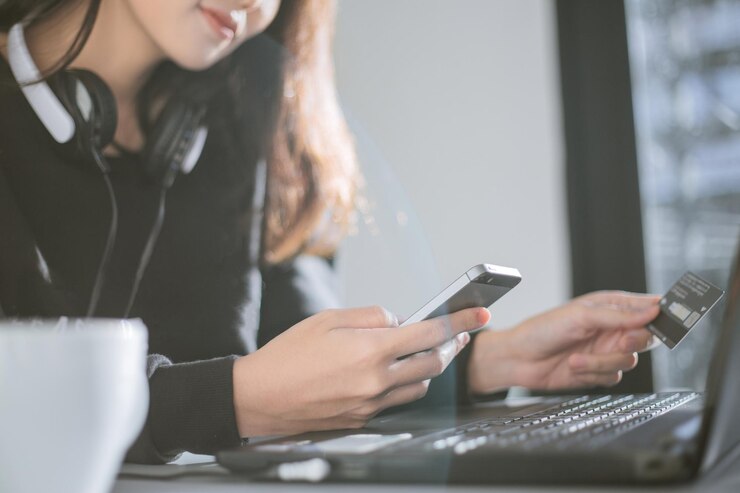 Photo 女性はスマートフォンとクレジットカードを持ってオンラインで買い物します