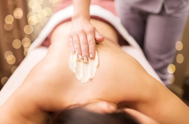 Photo woman having back massage with cream at spa