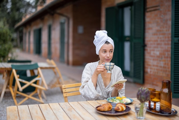 Женщина завтракает на террасе отеля на природе